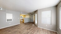 This single-floor residential unit offers a functional and well-organized layout designed for comfortable everyday living. The open-concept living area is finished with durable wood-look flooring in a warm brown tone, neutral gray walls, and clean white baseboards that create a cohesive, modern feel. A ceiling fan overhead adds both style and practicality, while multiple windows fitted with horizontal blinds allow for adjustable natural light throughout the space. A sliding glass door provides convenient access to the exterior.

The kitchen is positioned adjacent to the living area and separated by a half-wall counter, offering a semi-open connection between the two spaces. It features warm-toned cabinetry, light countertops, white appliances including a range and built-in microwave, a double stainless steel sink, and a dishwasher — all set on matching wood-look flooring.

Two well-proportioned bedrooms are finished with plush wall-to-wall carpeting and neutral paint, each with a window that invites natural light. The unit includes two full bathrooms, each equipped with a tub-shower combination, toilet, and vanity. One bathroom features wood-look flooring with a light wood-toned vanity, while the other is finished with tile flooring. Both bathrooms maintain a clean, simple aesthetic with brushed nickel hardware accents throughout.