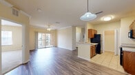 Located at 3000 Marta Cir in Kissimmee, Florida, this well-appointed single-floor residence offers three bedrooms, two bathrooms, and a thoughtfully organized layout. The open living area features wood-look laminate flooring, crown molding, a ceiling fan with light fixture, and a sliding glass door that fills the space with natural light and provides access to a private balcony. The kitchen is equipped with warm-toned wooden cabinetry, light countertops, black appliances including a refrigerator, electric range, and built-in microwave, and flows seamlessly into the living area via a peninsula with a sink. Tile flooring continues throughout the kitchen. Each bedroom is finished with plush carpeting and bright windows fitted with blinds, offering peaceful outdoor views. The spacious primary bedroom features two large windows for abundant natural light. Both bathrooms include tiled tub-and-shower combinations, wooden vanities, and tile flooring. A dedicated walk-in closet with built-in shelving and wire rack storage adds practical organization to the primary suite. A separate laundry room rounds out the functional layout of this comfortable Kissimmee home.