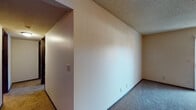 Located at 2759 North Amidon Street in Wichita, Kansas, this single-floor residence offers a practical and comfortable layout with a neutral color palette throughout. The living area is generously sized, featuring plush carpet flooring, a textured ceiling, and a sliding glass door fitted with vertical blinds that allows natural light to pour in while providing access to the outdoors. Adjacent to the living area, the kitchen is a standout space highlighted by a striking diagonal wood-paneled accent wall that adds warmth and character. The kitchen includes dark wood cabinetry, a tiled backsplash, a built-in dishwasher, and a breakfast bar countertop that connects to the living space. The bedrooms are carpeted and bathed in natural light through windows dressed with vertical blinds, offering a calm and restful atmosphere. The bathroom features light tile flooring, a vanity with a marbled countertop, dark wood cabinetry with overhead storage, and a separate tub and toilet area. A hallway connects the various areas of the home, providing a functional flow between spaces. Throughout, the home maintains a consistent and understated design with textured ceilings and warm neutral tones, making it a solid and move-in-ready residence in Wichita.