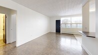Located at 1255 Birchmount Rd in Toronto, this one-bedroom, two-bathroom unit offers a well-organized and functional layout across a single floor. The open living room is a standout feature, showcasing classic parquet wood flooring that extends throughout the main living areas, a textured ceiling, and a large picture window that fills the space with natural light while offering views of the surrounding greenery. A baseboard heating system ensures year-round comfort.

The kitchen is thoughtfully designed with white cabinetry, dark countertops, a subway tile backsplash, and stainless steel appliances including a refrigerator, electric range, and built-in microwave. Light tile flooring and ceiling-mounted lighting give the kitchen a clean, modern feel. A half-wall partition separates it from the living area, maintaining an open yet defined flow.

The bedroom is a comfortable, well-proportioned retreat featuring the same parquet flooring, a large window with an exterior view, and a built-in mirrored sliding closet that adds both storage and a sense of depth to the room.

The bathroom is finished with white subway tile surrounding the soaker tub, a vanity with ample storage, and neutral stone-look floor tiles, creating a clean and timeless aesthetic throughout.