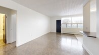 Located at 1255 Birchmount Rd in Toronto, this one-bedroom, two-bathroom unit offers a well-organized and functional layout across a single floor. The open living room is a standout feature, showcasing classic parquet wood flooring that extends throughout the main living areas, a textured ceiling, and a large picture window that fills the space with natural light while offering views of the surrounding greenery. A baseboard heating system ensures year-round comfort.

The kitchen is thoughtfully designed with white cabinetry, dark countertops, a subway tile backsplash, and stainless steel appliances including a refrigerator, electric range, and built-in microwave. Light tile flooring and ceiling-mounted lighting give the kitchen a clean, modern feel. A half-wall partition separates it from the living area, maintaining an open yet defined flow.

The bedroom is a comfortable, well-proportioned retreat featuring the same parquet flooring, a large window with an exterior view, and a built-in mirrored sliding closet that adds both storage and a sense of depth to the room.

The bathroom is finished with white subway tile surrounding the soaker tub, a vanity with ample storage, and neutral stone-look floor tiles, creating a clean and timeless aesthetic throughout.