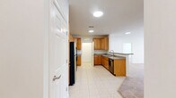 Located at 4645 Daisy Reid Ave in Woodbridge, VA, this 2-bedroom, 2-bathroom residence offers a well-organized single-floor layout designed for comfortable everyday living. The kitchen is a functional highlight, featuring warm honey-toned wood cabinetry with ample storage, granite-style countertops, tile flooring, and black appliances including a refrigerator, electric range, and built-in microwave. A stacked washer and dryer unit is conveniently integrated into the kitchen area, adding in-unit laundry functionality. The combined kitchen and living area flows naturally, with the living room finished in plush neutral carpeting and a sliding glass door that invites natural light and provides outdoor access. The spacious primary bedroom is a comfortable retreat, also carpeted, with a generous closet and access to a private en-suite bathroom featuring a glass-enclosed shower and tile floors. The second bedroom is well-proportioned with soft carpet, a large window offering outdoor views, and easy access to the second full bathroom, which includes a vanity with warm wood cabinetry and a mirror. Clean white walls throughout lend the home a bright, neutral palette, while six-panel doors add a classic touch. A dedicated utility room rounds out the practical amenities of this thoughtfully laid-out home.