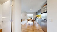 Located at 1888 Scotia St in Vancouver's Mount Pleasant neighbourhood, this thoughtfully designed one-bedroom, one-bathroom unit offers a well-organized layout across a single floor. Light hardwood flooring flows throughout, complementing the clean white walls and modern aesthetic.

The kitchen is a standout feature, showcasing sleek matte grey cabinetry, a vibrant yellow subway tile backsplash with under-cabinet lighting, stainless steel appliances, and open shelving. It opens directly to a dining area, creating an inviting, functional space.

The living room is bright and airy, with large windows drawing in natural light and a warm, neutral palette. A dedicated office nook provides a quiet workspace, complete with a built-in desk area — a practical addition to the layout.

The bedroom benefits from dual corner windows that frame urban views and fill the room with light. It includes a walk-in closet offering generous storage. The bathroom is finished with large-format white tiles, a walk-in shower, and a clean, minimalist design.

A private balcony extends the living space outdoors, offering city views. The entry opens directly to the kitchen, reinforcing the unit's efficient and open flow throughout.