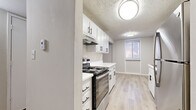 Located at 1012 Emery Rd in Lawrence, Kansas, this single-floor residence offers two bedrooms and two full bathrooms in a thoughtfully laid-out floor plan. The combined kitchen and living room area serves as the heart of the home, featuring light wood-style luxury vinyl flooring that creates a clean, cohesive aesthetic. The galley-style kitchen is well-appointed with crisp white cabinetry with black hardware, light-toned countertops, stainless steel appliances including a range and refrigerator, and a stainless steel sink — all complemented by a textured ceiling and flush-mount lighting. The open living area flows naturally from the kitchen, offering a bright, neutral canvas with ample room to arrange furnishings. Both bedrooms are finished with plush carpet and feature neutral walls that lend a calm, comfortable atmosphere. The spacious primary bedroom includes direct access to a full bathroom and a dedicated closet. A secondary bedroom benefits from a large window that invites natural light. A well-organized hallway closet provides additional built-in shelving for storage needs. The bathrooms are clean and functional, each featuring a full tub-shower combination. Two hallways connect the rooms efficiently, rounding out this practical and move-in-ready home.