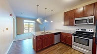 This 640 square foot apartment in Loveland, Ohio, offers a thoughtful blend of comfort and functionality. The single-floor layout comprises one bedroom, measuring 140 square feet, and two full bathrooms, providing ample personal space and convenience.

The heart of the home is the open-concept kitchen and living area. The kitchen boasts rich, warm-toned cabinetry, complemented by sleek granite countertops and stainless steel appliances. Pendant lighting adds a touch of modern elegance, while a kitchen island provides additional prep space and casual dining options.

The living area seamlessly connects to the kitchen, featuring hardwood flooring that extends throughout the main living spaces. Large windows, including a balcony door, flood the area with natural light and offer scenic views.

The bedroom is generously sized at 140 square feet, with plush carpeting and a large window that brings in ample daylight. The bathrooms are well-appointed, featuring modern fixtures, a granite-topped vanity, and continuing the hardwood flooring theme.

Storage is optimized with a dedicated closet space. The apartment's neutral color palette provides a versatile backdrop for various decor styles, allowing residents to personalize their living space easily.