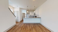 Located at 8303 Brandt Pike in Huber Heights, Ohio, this two-story home showcases a clean, contemporary design with thoughtfully selected finishes throughout. The main level features an open-concept layout where the living area flows seamlessly into the kitchen, creating a spacious and connected environment. Wood-look plank flooring extends across the main level, lending warmth and visual continuity to the space.

The kitchen is a standout feature, equipped with white shaker-style cabinetry accented by matte black hardware, granite countertops, and a full suite of stainless steel appliances including a refrigerator, range, and microwave. A peninsula with an integrated sink serves as both a functional workspace and a natural divider between the kitchen and living area, complemented by pendant lighting overhead.

Bathrooms on both levels feature granite-topped vanities with undermount sinks, wood-look flooring, and clean white walls. One bathroom includes a glass-enclosed shower, while another offers a windowed layout that brings in natural light.

The upper level houses the bedrooms, each finished with plush carpeting, bright white walls, and windows that allow ample natural light. The overall aesthetic is modern and neutral, providing a versatile backdrop throughout.