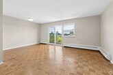 Located at 26-38 Carluke Crescent in Toronto's sought-after M2L neighbourhood, this two-bedroom, one-bathroom unit offers a well-organized single-floor layout with a functional and comfortable flow throughout. Warm parquet flooring runs consistently through the living areas and bedrooms, adding a classic character to the space.

The open living room is generously sized, bathed in natural light through large sliding glass doors that lead to a balcony, offering appealing views of the surrounding greenery and city skyline. Baseboard heating units are present throughout, ensuring year-round comfort.

The kitchen has been renovated with dark wood cabinetry extending to the ceiling for ample storage, marble-patterned countertops, a double stainless steel sink with a white subway tile backsplash, and stainless steel appliances including a refrigerator. Light tile flooring completes the clean, modern aesthetic.

The primary bedroom is a well-proportioned room featuring a window with views of the cityscape and surrounding trees. The second bedroom is a comfortable size with neutral tones and parquet flooring. The bathroom is finished in a crisp white palette with tile flooring, a full bathtub with shower, toilet, and a dark wood vanity with a white countertop. A hallway connects all rooms efficiently, rounding out this practical and inviting unit.