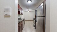 Located at 1267 11th Ave SW in Forest Lake, MN, this single-floor, 3-bedroom, 1-bathroom unit offers a practical and comfortable layout. The galley-style kitchen is a standout feature, equipped with stainless steel appliances including a refrigerator, range, microwave, and dishwasher, complemented by rich dark-cherry cabinetry and dark granite-look countertops. Light tile flooring runs throughout the kitchen, which also benefits from a ceiling fan for added comfort. The living areas are carpeted and open in feel, with ceiling fans providing airflow. The generously sized primary bedroom features a sliding glass door that lets in natural light and offers views of the surrounding greenery, along with a wall-mounted A/C unit and baseboard heating. The additional bedrooms are well-proportioned with carpeted floors, baseboard heating, and windows that bring in natural light and outdoor views. The bathroom is clean and functional, featuring a full tub and shower combination with accessibility grab bars and tile flooring. A connecting hallway ties the layout together efficiently. The textured ceilings and warm wood trim throughout lend a consistent, cohesive look to the entire unit.