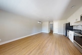This thoughtfully designed 2-bedroom, 1-bathroom single-story home offers a clean, modern aesthetic throughout. Warm hardwood-style flooring flows seamlessly across the entire interior, creating a cohesive and inviting atmosphere. The open-concept kitchen and living area serves as the heart of the home, featuring white shaker cabinetry, dark countertops, a subway tile backsplash, and a full suite of stainless steel appliances including a refrigerator, range, microwave, and dishwasher. A wall-mounted mini-split unit provides efficient climate control in both the main living area and the primary bedroom. The two bedrooms are well-proportioned, each finished with the same warm flooring and neutral wall tones. The primary bedroom includes a dedicated mini-split unit, while the second bedroom benefits from large windows offering views of the lush, landscaped surroundings. The bathroom is neatly finished with built-in shelving and a stone-toned countertop vanity. A dedicated laundry room houses a stacked washer and dryer unit for added convenience. Outside, a wood-railed patio opens to beautifully maintained community grounds with mature trees, ornamental plantings, and walkways — creating a peaceful and welcoming environment.