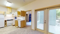 Located at 12740 30th Avenue NE in Seattle, WA, this single-floor unit offers a practical and well-organized layout suited for comfortable everyday living. The kitchen is equipped with wood-toned cabinetry extending to the upper walls for generous storage, a full-size refrigerator, electric range, dishwasher, and a sink with ample counter space. Light wood-style flooring runs throughout the kitchen and entry areas, creating a clean and cohesive look. The living area is carpeted and bathed in natural light, thanks to a set of glass French doors that open to an outdoor patio, offering a pleasant connection to the greenery outside. A dedicated entry closet with a hanging rod and shelving provides convenient storage near the front of the unit. The bedroom is a quiet, carpeted room with neutral tones and a baseboard heating unit. A reach-in closet offers additional storage within the bedroom. The bathroom features wood-framed cabinetry with an integrated vanity sink, a large mirror with overhead lighting, light wood-style flooring, and a grab bar for added accessibility. Overall, the unit presents a clean, neutral palette with warm wood accents throughout, offering a functional and inviting living environment in a residential Seattle neighborhood.