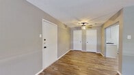 This single-story space is designed with a consistent, cohesive aesthetic carried throughout every room. Wood-look plank flooring runs continuously across all areas, providing warmth and visual continuity, while neutral gray wall tones create a calm, versatile backdrop.

The entry area opens into a well-proportioned room featuring a ceiling fan with integrated lighting and two interior doors — likely leading to closets or additional rooms — offering practical storage and accessibility from a central point. A separate, generously sized living area benefits from natural light admitted through a window fitted with horizontal blinds.

The bedrooms are each equipped with ceiling fans and windows that allow natural light to filter in, contributing to a bright and comfortable atmosphere. Closet access is present in at least one bedroom.

The kitchen features white cabinetry, light quartz-style countertops, a classic subway tile backsplash, and stainless steel appliances including a gas range and over-the-range microwave, forming a clean, functional cooking space.

The bathroom is finished in a clean, minimal style with wood-look flooring, a wall-mounted vanity with mirror, overhead lighting, overhead storage cabinetry, and a tub-shower combination — delivering straightforward, practical functionality.