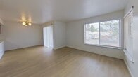 Located at 301 E 45th St in Vancouver, WA, this single-floor apartment offers 910 square feet of thoughtfully designed living space across 2 bedrooms and 2 bathrooms. The unit features light hardwood-style flooring throughout, creating a cohesive and bright aesthetic.

The open living room is bathed in natural light through large windows with blinds and includes a sliding glass door, offering outdoor views of surrounding greenery. The kitchen is well-appointed with light wood cabinetry, white quartz countertops, and a full suite of stainless steel appliances including a refrigerator, electric range, and dishwasher.

The primary bedroom measures 170 square feet and features a distinctive bay window that floods the room with natural light, along with a baseboard heater and a dedicated closet. The second bedroom is also generously sized with a window and baseboard heating. Both bathrooms are finished with light wood vanities, white quartz countertops, and black-framed mirrors. One bathroom includes a walk-in shower, while the other features a full shower/tub combo with chrome fixtures. The unit is completed by two closets and a utility room for additional storage.