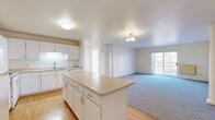 Located at 2390 Ridgeview Dr in Eau Claire, Wisconsin, this 2-bedroom, 2-bathroom single-floor residence offers a practical and comfortable layout. The open-concept kitchen flows seamlessly into the living room, creating a connected and functional living space. The kitchen is well-equipped with white cabinetry, a full suite of white appliances including a refrigerator, electric range, and microwave, and a central island that provides additional prep space and storage. Light hardwood-style flooring runs through the kitchen and extends into the laundry area.

The living room features plush carpeting and a sliding glass door that fills the room with natural light while providing access to an outdoor area with neighborhood views. Both bedrooms are carpeted, bright, and generously sized, with windows allowing in ample natural light. The primary bedroom offers a comfortable retreat with its own closet.

The two bathrooms each feature a tub-shower combination, a white vanity, and warm-toned tile flooring. A dedicated in-unit laundry room houses a full-size washer and dryer, adding everyday convenience. Baseboard heating is present throughout the home. The overall aesthetic is clean and neutral, offering a move-in ready environment.