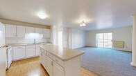 Located at 2390 Ridgeview Dr in Eau Claire, Wisconsin, this 2-bedroom, 2-bathroom single-floor residence offers a practical and comfortable layout. The open-concept kitchen flows seamlessly into the living room, creating a connected and functional living space. The kitchen is well-equipped with white cabinetry, a full suite of white appliances including a refrigerator, electric range, and microwave, and a central island that provides additional prep space and storage. Light hardwood-style flooring runs through the kitchen and extends into the laundry area.

The living room features plush carpeting and a sliding glass door that fills the room with natural light while providing access to an outdoor area with neighborhood views. Both bedrooms are carpeted, bright, and generously sized, with windows allowing in ample natural light. The primary bedroom offers a comfortable retreat with its own closet.

The two bathrooms each feature a tub-shower combination, a white vanity, and warm-toned tile flooring. A dedicated in-unit laundry room houses a full-size washer and dryer, adding everyday convenience. Baseboard heating is present throughout the home. The overall aesthetic is clean and neutral, offering a move-in ready environment.