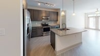 This single-floor residence at 109 Knox Abbott Drive in Cayce, South Carolina, presents a clean, contemporary design throughout its well-appointed layout. The open-concept living area is anchored by light wood-look flooring and a ceiling fan, with large glass doors that invite natural light and provide outdoor views, creating a bright and welcoming atmosphere.

The kitchen is a standout feature, outfitted with dark espresso cabinetry, granite countertops, a subway tile backsplash, and a full suite of stainless steel appliances, including a refrigerator, electric range, and built-in microwave. A peninsula with an integrated sink and pendant lighting overhead adds both function and style, making it an ideal space for cooking and entertaining.

Bedrooms are finished with plush carpet, ceiling fans, and natural light from windows with blinds. Walk-in closets with wire shelving systems provide generous storage. The bathroom features large-format tile flooring, a dark-stained vanity with a granite countertop, and a full tub-shower combination with neutral tile surround. An in-unit laundry area with wire shelving and washer hookup adds everyday convenience throughout this thoughtfully designed space.