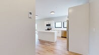 Located at 27S Main St in Attleboro, MA, this thoughtfully designed one-bedroom, one-bathroom unit offers a clean, modern aesthetic across a single floor. Light-toned hardwood flooring runs throughout the entire space, creating a bright and cohesive feel from room to room.

The heart of the unit is the open-concept kitchen, dining, and living area. The kitchen is a standout feature, boasting white shaker-style cabinetry with matte black hardware, a marble-look quartz center island, white subway tile backsplash, and a full suite of stainless steel appliances including a range, microwave, dishwasher, and refrigerator. Multiple windows invite abundant natural light into the space.

The living area is generously proportioned and includes a large sliding glass door that opens to an outdoor view of the surrounding greenery, enhancing the sense of openness. The bedroom is a comfortable and well-lit retreat with dual windows framing outdoor views and two closets providing ample storage. The bathroom features a clean, all-white tub and shower surround with chrome fixtures. A dedicated utility room and additional storage complete the functional layout of this move-in ready unit.