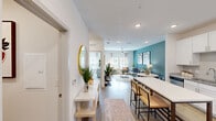 Located at 1290 Kendall Town Blvd in Jacksonville, FL, this one-bedroom, one-bathroom residence offers a thoughtfully designed single-floor layout with modern finishes throughout. The kitchen is a standout feature, showcasing crisp white shaker cabinets, granite countertops, a subway tile backsplash, and a full suite of stainless steel appliances including a refrigerator, range, microwave, and dishwasher. A kitchen island with seating provides additional prep and dining space, all set over durable wood-look flooring. The living room is bright and inviting, featuring large windows that invite natural light, a ceiling fan, and a bold teal accent wall that adds a vibrant pop of color and personality. The bedroom continues the teal accent wall theme and is fitted with plush carpeting, a ceiling fan, and windows with outdoor views, creating a comfortable and restful retreat with a dedicated closet for storage. The bathroom offers white cabinetry, granite countertops, and wood-look flooring, maintaining the cohesive, contemporary aesthetic found throughout the home. A dedicated laundry room with a full-size washer and dryer adds everyday convenience, completing this well-appointed residence.