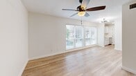 Located in Dallas's vibrant Oak Lawn neighborhood, this well-designed one-bedroom, two-bathroom home offers a clean, modern aesthetic throughout its single floor. Light-toned hardwood flooring runs continuously across all rooms, creating a cohesive and airy feel.

The living room is bright and welcoming, featuring large sliding windows that draw in abundant natural light and offer views of the surrounding greenery. A ceiling fan overhead adds both style and functionality. The space flows naturally toward the kitchen area, which is visible in the corner of the room.

The bedroom is a comfortable retreat, equipped with its own ceiling fan and a window overlooking outdoor greenery. A door leads directly into a dedicated walk-in closet, providing generous storage. The bathroom accessible from the bedroom includes subway tile accents on the walls, wood-look flooring, and a soaking tub.

The second bathroom stands out with its refined finishes, including gray shaker-style cabinetry, a white quartz countertop, an undermount sink, and a black-framed rectangular mirror. A three-bulb vanity light fixture adds bright, even illumination, while light wood flooring ties the room together.

Throughout the home, a consistent palette of white walls, light wood floors, and black hardware accents delivers a clean, contemporary look that feels both fresh and functional.