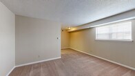 This single-floor, 2-bedroom, 1-bathroom unit offers a practical and well-organized layout designed to maximize every square foot of available space. Throughout the home, warm beige carpeting and neutral-toned walls create a clean, cohesive aesthetic that provides a versatile backdrop for a variety of décor styles.

The spacious primary bedroom is the standout feature of this unit, offering generous room for furnishings and comfortable living. It is outfitted with a ceiling fan with integrated lighting, providing both air circulation and illumination. A dedicated closet with built-in shelving adds convenient storage directly within the room.

The second bedroom is comparably well-sized and also features a ceiling fan with a light fixture. Its neutral walls and plush carpeting maintain the consistent, welcoming feel found throughout the home. A window in this room allows for natural light to filter in.

The remaining areas of the home, visible in the floor plan, include a centrally located kitchen with cabinetry, connecting the living areas in a functional arrangement. The textured ceilings seen in some rooms add a subtle architectural detail consistent with the home's straightforward design. Overall, this unit presents a tidy and efficient living space suited for those seeking comfort and practicality in a single-level layout.