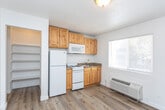 Located at 821 S 475 W in Cedar City, Utah, this efficient single-floor unit offers a practical and well-organized layout across one bedroom and two bathrooms. Light wood laminate flooring runs throughout the entire space, creating a cohesive, clean aesthetic.

The kitchen is a functional highlight, featuring warm knotty pine cabinetry extending from floor to ceiling, granite-style dark countertops, and white appliances including a refrigerator, electric range, and over-the-range microwave. A large window fitted with blinds allows ample natural light into the kitchen area. A wall-mounted HVAC unit provides climate control convenience.

The primary bedroom is comfortably sized with crisp white walls, light wood flooring, and a window that brings in natural light. The room offers a calm, neutral environment well-suited for rest.

A hallway connects the main living areas to the bathrooms and includes built-in open shelving for added storage. One bathroom features a full bathtub-shower combination with marble-style wall surround paneling and a vanity with warm wood cabinetry. The overall layout is straightforward and easy to navigate.

This unit presents a clean, no-frills interior with consistent finishes throughout, making it a practical option for those seeking a compact and functional living space in Cedar City.