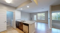 This single-floor unit offers a thoughtfully designed layout that maximizes functionality across its living spaces. The open-concept kitchen and living area serves as the heart of the unit, where light hardwood-style flooring, recessed lighting, and a large window with balcony access create a bright, welcoming atmosphere. The kitchen is well-equipped with dark espresso cabinetry, granite countertops, a mosaic tile backsplash, a stainless steel appliance suite including a refrigerator, range, microwave, and dishwasher, and a peninsula with an undermount sink that doubles as a casual dining or prep area.

The living area benefits from natural light streaming through large windows and a glass-panel balcony door, offering views of surrounding greenery. The bedroom features plush carpeting, a sizable window with tree views, and direct access to a dedicated walk-in closet equipped with wire shelving and hanging rods for organized storage. The bathroom presents a double-sink vanity with granite counters, dark cabinetry, a large mirror, and a full tub-shower combination, all finished with wood-look flooring for a cohesive, modern aesthetic throughout.