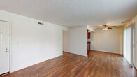 This well-appointed one-bedroom, one-bathroom residence in Lafayette, Indiana offers a functional and comfortable single-floor layout. The open living area is highlighted by rich, dark hardwood-style flooring that flows throughout the main living spaces, neutral cream-toned walls, and a textured ceiling. A ceiling fan keeps the space comfortable, while a sliding glass door and a large window allow natural light to fill the room and provide outdoor views. The kitchen is positioned adjacent to the living area and features a galley-style layout with warm, dark wood cabinetry, granite-toned countertops, a double-basin stainless steel sink, and black appliances including a refrigerator, range, and dishwasher. A sliding glass door at the end of the kitchen offers additional light and access. The bedroom offers a cozy retreat with plush carpeting, a natural light-filled window, and convenient access to both a walk-in closet outfitted with dual wire shelving systems and an additional door. The full bathroom includes a tub-shower combination with a clean, neutral surround. A dedicated hallway connects all areas of the home, completing this efficient and inviting layout.