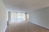 Located at 11225 Oak Leaf Dr in Silver Spring, MD, this single-floor residence offers four bedrooms, two bathrooms, and a well-organized layout across a generously sized floor plan. The living room is a standout space, featuring wall-to-wall carpeting, a textured ceiling, and expansive floor-to-ceiling vertical blinds that flood the room with natural light and provide access to outdoor views. The adjoining dining area continues the bright, open feel with large windows overlooking lush greenery and a pendant light fixture as a central design detail. The kitchen is thoughtfully updated with white shaker-style cabinetry, dark granite countertops, a tiled backsplash, and black appliances including a gas range, dishwasher, and built-in microwave, all set over light hardwood-style flooring. Each of the four bedrooms is carpeted and includes its own closet — several featuring louvered bi-fold doors with built-in shelving — providing ample storage throughout. The two bathrooms are finished with full-height neutral tile surrounding the tub-shower combinations, white vanities, and clean, functional layouts. A dedicated laundry area adds everyday convenience. The overall ambiance is clean, neutral, and move-in ready.