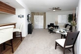 This thoughtfully designed two-bedroom, two-bathroom residence is laid out entirely on a single floor, offering a comfortable and functional living experience. The open living and dining area is bright and welcoming, featuring plush carpeting, a ceiling fan, and large sliding glass doors and windows that invite abundant natural light. The adjacent dining space provides a seamless flow for everyday living and entertaining.

The galley-style kitchen is efficiently arranged with cream cabinetry lining both sides, light wood-toned countertops, a stainless steel sink, and black appliances including a refrigerator and dishwasher. Wood-look flooring runs throughout the kitchen and connects directly to a dedicated in-unit laundry area, a notable convenience feature tucked just off the kitchen.

Both bedrooms are generously proportioned with soft carpeting and ceiling fans. The primary bedroom features large windows with outdoor views, while the second bedroom offers its own comfortable layout. Each of the two full bathrooms includes a tub-shower combination with tile surround and wood-look flooring, maintaining a clean, consistent aesthetic throughout.

Overall, the residence presents a neutral, light-filled palette with practical finishes and a well-connected floor plan that maximizes functionality across every room.