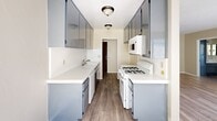 Located at 7050 Jordan Ave in the Canoga Park neighborhood of Los Angeles, this single-floor residence offers a well-organized layout across a compact but efficient footprint. Light-toned luxury vinyl plank flooring runs throughout, lending a clean, cohesive look to every room.

The galley-style kitchen is a standout feature, lined on both sides with two-toned cabinetry — dark upper cabinets with a glossy finish paired with lighter lower cabinets — all topped with bright white countertops. A gas range, built-in microwave, dishwasher, and a deep single-basin sink provide full functionality. Flush-mount ceiling fixtures illuminate the space effectively.

The kitchen opens directly into the combined dining and living area, creating a natural flow ideal for everyday living. A ceiling fan overhead and a large sliding glass door with vertical blinds allow natural light to pour in while offering access to an outdoor view of surrounding greenery and neighboring structures.

The bedroom is comfortably sized and features a full-width mirrored sliding closet, which adds depth and brightness to the room. A textured ceiling is consistent throughout the unit.

The bathroom is clean and straightforward, featuring a full tub-shower combination, a toilet, and light wood-tone flooring that ties back to the rest of the unit's finishes. The overall ambiance is bright, neutral, and move-in ready.