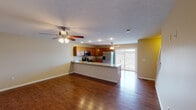 This three-floor home offers a thoughtfully designed layout with a blend of practical finishes and comfortable living spaces throughout. The main level centers around an open-concept kitchen and living area, unified by rich hardwood flooring and ceiling fans with integrated lighting. The kitchen is well-appointed with warm honey-toned cabinetry, granite-style countertops, and a full suite of stainless steel appliances including a range, over-the-range microwave, and a French door refrigerator. A peninsula with a sink provides additional prep space and casual seating, while a sliding glass door floods the area with natural light and offers views of the surrounding neighborhood. The living area is generously proportioned, creating an airy, open atmosphere ideal for everyday living and entertaining. Carpeted bedroom spaces are found on the upper level, each featuring ceiling fans and neutral wall tones that provide a calm, restful environment. Multiple full bathrooms are distributed across the floors, each featuring tiled flooring, vanities with storage, and tub-shower combinations. A half bath with hardwood flooring serves as a convenient powder room. The attached garage completes the home, offering concrete flooring, an automatic door opener, and a baseboard heater for year-round utility.