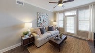 This single-floor residence offers a thoughtfully designed layout that balances comfort and modern style. The living area serves as a welcoming focal point, featuring rich hardwood-style flooring, a ceiling fan, and large windows dressed with white curtains that invite natural light while maintaining privacy. Bold abstract artwork adds a contemporary touch, complementing the neutral, warm-toned walls throughout the space.

The kitchen is outfitted with dark espresso cabinetry, granite countertops, a classic subway tile backsplash, and a full suite of stainless steel appliances, including a refrigerator, range, microwave, and dishwasher. Hardwood-style flooring continues here, lending a cohesive feel to the common areas.

The bedrooms are carpeted for comfort and each features a ceiling fan, ample natural light from well-sized windows, and thoughtful design details. One bedroom showcases a warm wood-paneled headboard and coordinating nightstands, while another is accented by colorful abstract art and soft layered bedding.

The bathrooms are finished consistently with dark cabinetry, granite-topped vanities, and hardwood-style flooring. Each bathroom includes a tub-shower combination with tile surround, providing a clean and functional design. Overall, the space presents a cohesive, modern aesthetic with quality finishes at every turn.