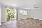 This one-bedroom, one-bathroom unit offers a thoughtfully organized layout that makes efficient use of its single-floor footprint. The living room serves as the central gathering space, distinguished by hardwood-style flooring, crown molding, and a ceiling fan. Large sliding glass doors open onto a private balcony with outdoor views of surrounding greenery, while an adjacent window allows abundant natural light to fill the room, creating a bright and welcoming ambiance.

The kitchen is accessed via a hallway and features light wood cabinetry with ample storage, granite-style countertops, a double-basin sink, and stainless steel appliances including a refrigerator and range, all set over hardwood-style flooring.

The bedroom is a generously sized retreat carpeted for comfort, equipped with a ceiling fan, a natural light source through a horizontal window, and a built-in closet with bifold doors providing practical storage. The hallway also includes an additional dedicated closet for extra storage convenience.

The bathroom is clean and functional, featuring a full tub-shower combination with a curved curtain rod, chrome fixtures, and coordinating hardwood-style flooring. Neutral gray tones throughout the unit contribute to a cohesive and modern aesthetic.