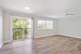 This one-bedroom, one-bathroom unit offers a thoughtfully organized layout that makes efficient use of its single-floor footprint. The living room serves as the central gathering space, distinguished by hardwood-style flooring, crown molding, and a ceiling fan. Large sliding glass doors open onto a private balcony with outdoor views of surrounding greenery, while an adjacent window allows abundant natural light to fill the room, creating a bright and welcoming ambiance.

The kitchen is accessed via a hallway and features light wood cabinetry with ample storage, granite-style countertops, a double-basin sink, and stainless steel appliances including a refrigerator and range, all set over hardwood-style flooring.

The bedroom is a generously sized retreat carpeted for comfort, equipped with a ceiling fan, a natural light source through a horizontal window, and a built-in closet with bifold doors providing practical storage. The hallway also includes an additional dedicated closet for extra storage convenience.

The bathroom is clean and functional, featuring a full tub-shower combination with a curved curtain rod, chrome fixtures, and coordinating hardwood-style flooring. Neutral gray tones throughout the unit contribute to a cohesive and modern aesthetic.