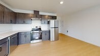 Located at 1000 S Holladay Dr in Seaside, Oregon, this single-floor, one-bedroom, one-bathroom unit offers a thoughtfully designed layout with modern finishes throughout. Light-toned luxury vinyl plank flooring runs continuously across every room, creating a clean, cohesive aesthetic. The open-concept kitchen and living area forms the heart of the unit, filled with natural light from multiple windows and a glass door leading to a private balcony. The kitchen is well-appointed with dark espresso shaker-style cabinetry, stainless steel appliances including a range, dishwasher, and refrigerator, light countertops, and an overhead range hood. The living area benefits from recessed lighting and direct balcony access, where serene views of a nearby wetland and water body can be enjoyed. The bedroom is a comfortable, quiet retreat featuring a window with natural light and an adjacent closet for dedicated storage. The full bathroom includes a tub-shower combination, a dark-cabinet vanity with a white countertop, and matte black fixtures. A dedicated laundry area and hallway complete the floorplan. The unit's clean, contemporary design and natural surroundings make it a practical and appealing residence in coastal Seaside.
