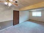 This single-story unit offers two bedrooms and one-and-a-half bathrooms within a practical, easy-to-navigate floor plan. The living area features carpet flooring, a ceiling fan with a light fixture, and a window that allows natural light to filter in. A two-toned wall treatment with gray and white adds a subtle design detail to the space. The living area flows into an adjoining carpeted zone, separated by a structural beam overhead, creating a natural division within the open layout.

The kitchen is equipped with warm-toned wood cabinetry, light wood-finish countertops, a stainless steel sink, and a dishwasher. Tile flooring and louvered closet doors add functional touches to the space. Both bedrooms are carpeted and feature windows with blinds that bring in natural light, keeping the rooms feeling bright and airy. The primary bedroom includes access to a full bathroom, which offers a wood-vanity with a marble-style countertop, a large mirror, and a tub-shower combination with a white surround. A half bathroom provides additional convenience. The overall ambiance is clean, neutral, and functional.