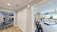 Located at 5000 S Lincoln Trace Ave SE in Smyrna, Georgia, this fitness center is a thoughtfully designed, single-floor facility offering a generous and well-organized workout environment. The space is divided into two dedicated exercise rooms connected by a hallway, each serving distinct fitness purposes.

The main cardio room is bathed in natural light from a wide bank of large windows that frame lush, green outdoor views. Ceiling fans circulate fresh air throughout the space, which features stylish patterned carpet in muted tones with teal accents. This room is outfitted with treadmills, elliptical trainers, a recumbent bike, and upright cycles, each paired with wall-mounted flat-screen TVs for an engaging workout experience.

A second exercise room, finished with warm hardwood-style flooring and clean white walls adorned with colorful artwork, houses a row of screen-equipped stationary spin bikes and a wall mirror — ideal for cycling classes or focused training sessions. Crown molding and recessed lighting lend a polished, upscale feel to the space.

Strength and functional training needs are addressed through a dedicated area featuring cable machines, weight benches, a medicine ball rack, resistance bands, stability balls, and a multi-use functional trainer. The facility is bright, clean, and well-maintained, creating an inviting and motivating atmosphere for residents.