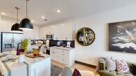 Located at 2180 Pickens Street in Columbia, SC, this thoughtfully designed one-bedroom, one-bathroom residence offers a refined living experience within a modern multi-story building. Light wood-tone flooring flows throughout, creating a warm and cohesive aesthetic across the single-level floor plan.

The kitchen is a standout feature, boasting crisp white shaker cabinetry reaching to the ceiling, granite countertops, stainless steel appliances, and a striking dark hexagonal tile backsplash. A generously sized island with seating and pendant lighting overhead makes this space ideal for both cooking and entertaining.

The spacious primary bedroom is a serene retreat, featuring a ceiling fan, built-in shelving, and a large window that invites natural light and offers views of the surrounding neighborhood. The en-suite bathroom continues the upscale design with a granite-topped double vanity, matte black fixtures, and a walk-in shower with tile surround.

A dedicated laundry room with a stacked washer and dryer unit and built-in wire shelving adds practical convenience. The balcony provides elevated views of a well-landscaped courtyard with palm trees, lounge seating, and a pool area, with a sports stadium visible in the distance—placing residents at the heart of Columbia's vibrant urban scene.