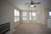 This single-floor home offers a comfortable and functional layout designed for everyday living. The main living area is generously proportioned, featuring warm beige carpet, a ceiling fan with light fixture, and a decorative arched fireplace flanked by windows that invite ample natural light. An adjacent area opens to a private balcony through sliding glass doors, extending the living space outdoors with views of surrounding greenery.

The open-concept layout connects the living area to a dining space and kitchen, which is outfitted with warm honey-toned wood cabinetry, dark granite-style countertops, tile flooring, and a full suite of black appliances including a range, over-the-range microwave, refrigerator, and dishwasher. A built-in desk area with matching cabinetry provides a convenient workspace just off the main living zone.

The bedrooms are carpeted and generously sized, each featuring walk-in closets with built-in shelving for organized storage and windows providing natural light. Two full bathrooms serve the home, both finished with patterned tile flooring, white vanities with dark countertops, and a tub-shower combination. The overall aesthetic throughout is neutral and clean, with warm beige tones creating a cohesive and inviting atmosphere.