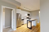Located in Port Moody, BC, this three-bedroom, one-bathroom apartment offers a well-organized single-level layout designed to maximize functionality. The entrance leads into a bright hallway finished with light-toned laminate flooring that extends throughout the main living areas, creating a clean and cohesive aesthetic.

The modern kitchen is a standout feature, equipped with stainless steel appliances including a range, over-the-range microwave, and dishwasher. Flat-panel white cabinetry reaches to the ceiling, complemented by a white tile backsplash and light stone countertops, delivering a sleek, contemporary look.

The living room connects to a private balcony, offering an outdoor retreat. Three bedrooms are carpeted for comfort, with the secondary bedrooms featuring large windows that bring in natural light. One bedroom includes direct access to a dedicated closet. Additional closet spaces are distributed throughout the unit for ample storage.

The bathroom is finished with large-format tile flooring and features a soaker tub with a tiled surround, a wood-toned vanity with an undermount sink, and a well-lit mirror. In-unit laundry adds everyday convenience. The unit presents a clean, neutral palette throughout, making it a practical and modern living space.
