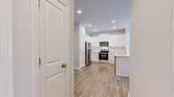 Located at 133 Cox St in Tonganoxie, Kansas, this single-story, one-bedroom, one-bathroom unit offers a thoughtfully designed layout that maximizes its compact footprint. The interior features a consistent neutral color palette with crisp white trim throughout, creating a clean and cohesive aesthetic.

The kitchen is a standout feature, equipped with white shaker-style cabinetry, a subway tile backsplash, stainless steel appliances including a refrigerator, range, and over-the-range microwave, and a sink with adjacent counter space. Wood-look luxury vinyl plank flooring runs through the kitchen and living areas, adding warmth and durability.

The living room is an open, well-lit space featuring a ceiling fan with recessed lighting, a large sliding glass door that invites natural light and outdoor views, and direct access to the hallway. The neutral walls provide a versatile backdrop for furnishing.

The bedroom is carpeted for comfort, fitted with a ceiling fan, and includes natural light from a window with blinds. A dedicated closet provides storage. The bathroom features wood-look tile flooring, a vanity with ample cabinetry, a soaking tub, and clean white fixtures. A hallway connects all rooms efficiently, completing this well-organized, move-in-ready space.