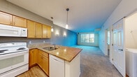 Located at 317 37th Ave NE in Columbia Heights, Minnesota, this one-bedroom, one-bathroom unit is thoughtfully laid out across a single floor, offering a comfortable and functional living space. The open-concept kitchen flows directly into the living room, creating a connected and airy feel. The kitchen features warm honey-toned wood cabinetry, granite-style countertops with a peninsula and built-in sink, pendant lighting, and white appliances including a refrigerator, electric range, microwave, and dishwasher. Durable wood-look flooring ties the kitchen together, while plush carpet extends through the living room and bedroom. The spacious living room is bright and inviting, with large windows fitted with vertical blinds that allow ample natural light and outdoor views, complemented by a sliding glass door providing additional access. The bedroom is a comfortable retreat with carpeted floors, a generous window, and access to a dedicated closet. The full bathroom is well-appointed with light wood cabinetry, a wide vanity with a white countertop, a large mirror, and a tub-shower combination with grab bars. The overall aesthetic is clean, neutral, and move-in ready, with consistent warm tones throughout the space.