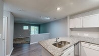 Located at Buckingham Station in Midlothian, VA, this two-bedroom, one-bathroom residence offers a comfortable and thoughtfully designed single-floor layout. The kitchen is a standout feature, showcasing granite countertops, white shaker cabinetry, stainless steel appliances including a range, microwave, and dishwasher, and a peninsula with a double-basin sink — ideal for both cooking and casual dining. Wood-look flooring in the kitchen and main areas adds warmth and durability throughout.

The living area is generously sized with soft carpeting, neutral gray walls, and a sliding glass door that opens to a private wooden deck. The deck is surrounded by lush, mature trees, providing a peaceful, natural backdrop and a pleasant space for outdoor relaxation.

Both bedrooms feature plush carpeting and large windows that invite natural light and wooded views. The primary bedroom includes a walk-in closet with built-in shelving, providing ample storage. The full bathroom is well-appointed with a tub-shower combo featuring white tile surround, granite-topped vanity, and wood-look flooring. A dedicated closet rounds out the functional storage in this well-organized residence nestled in a serene, tree-lined setting.