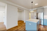 Located at 873 Communipaw Avenue in Jersey City, NJ, this modern 2-bedroom, 2-bathroom residence offers a thoughtfully designed single-floor layout with a clean, contemporary aesthetic. Warm wood-tone flooring runs throughout, complementing the bright white walls and creating a cohesive, inviting atmosphere.

The open-plan kitchen and living area serves as the heart of the home. The kitchen is outfitted with two-tone cabinetry in soft blue and light gray, white countertops, a textured tile backsplash, stainless steel appliances, and a peninsula island with a pendant light overhead. Large sliding glass doors in the living area flood the space with natural light and open directly onto a private balcony, offering outdoor views. A wall-mounted split AC unit provides efficient climate control.

The spacious primary bedroom also benefits from balcony access and generous natural light. Both bathrooms are finished with clean, modern fixtures — one featuring a deep soaking tub with large-format tile surround, and the other a floating vanity with a vessel sink and vertical subway tile backsplash.

Additional highlights include a versatile den, dedicated in-unit laundry, and three closets providing ample storage. The overall ambiance is fresh, bright, and move-in ready.