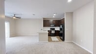 Located at 901 Hidden Valley Drive in Round Rock, Texas, this one-bedroom, one-bathroom unit offers a thoughtfully arranged single-floor layout that maximizes its compact footprint. The open-concept kitchen and living area serve as the heart of the home, where rich dark-espresso cabinetry pairs with a white subway tile backsplash and a generous quartz peninsula countertop complete with an undermount sink. Black appliances, including a refrigerator, range, and microwave, add a cohesive, modern contrast. Recessed lighting illuminates the kitchen, while the adjacent living area benefits from a ceiling fan and plush, neutral-toned carpeting underfoot. A sliding glass door opens directly to a private outdoor patio, filling the living space with natural light and providing a seamless indoor-outdoor connection. The bedroom is a comfortable retreat, featuring soft carpet, a ceiling fan with light fixture, and dual windows dressed with blinds that bring in ample daylight and neighborhood views. A dedicated closet provides convenient storage. The bathroom continues the design language of the home with a dark wood vanity, quartz countertop, framed mirror, and a full soaking tub with large-format tile surround, all set on warm wood-look flooring that ties the space together cohesively.
