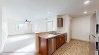 This single-floor residence in Owatonna, Minnesota offers a well-designed layout with three bedrooms, one bathroom, and a thoughtfully arranged living space. The open-concept kitchen flows directly into the living room, creating a connected and functional common area. The kitchen is outfitted with rich dark-stained cabinetry, granite-look countertops, a stainless steel dishwasher, refrigerator, and a double-basin sink, all set above warm light hardwood-style flooring. A ceiling fan anchors the living room, which receives generous natural light through multiple windows fitted with horizontal blinds.

The three bedrooms are carpeted and bright, each featuring windows that bring in natural light and outdoor views. The primary bedroom is notably spacious and includes a walk-in closet with wire shelving. One bedroom also features a tray ceiling detail with a ceiling fan, adding architectural interest. The full bathroom is finished with matching dark wood cabinetry, a white countertop vanity, a framed mirror with overhead lighting, and the same light hardwood-style flooring found in the kitchen. Throughout the home, light-toned trim and neutral wall colors create a clean, cohesive aesthetic.