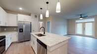 This single-story residence in Austin, TX (78723) offers a thoughtfully designed open-concept layout with contemporary finishes. The kitchen serves as a central highlight, featuring a large island with a granite countertop, an undermount sink with a matte black faucet, and white shaker cabinetry. Stainless steel appliances — including a French door refrigerator, electric range, microwave, and dishwasher — complement a subtle gray tile backsplash. Pendant lighting above the island adds a refined touch, while light wood-look flooring extends seamlessly into the living area.

The living room is bright and welcoming, with French doors that invite natural light and provide outdoor access. A ceiling fan adds functionality to the open space. Bedrooms are carpeted for comfort, each featuring natural light through slatted blinds and ceiling fans.

The primary bathroom offers a double-sink vanity with granite counters, matte black fixtures, large-format tile flooring, and a glass-enclosed shower. A secondary bathroom mirrors the quality with granite counters, tiled tub-shower surround, and black hardware accents. A dedicated laundry area with full-size washer and dryer hookups and built-in shelving completes the practical layout.