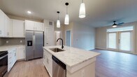 This single-story residence in Austin, TX (78723) offers a thoughtfully designed open-concept layout with contemporary finishes. The kitchen serves as a central highlight, featuring a large island with a granite countertop, an undermount sink with a matte black faucet, and white shaker cabinetry. Stainless steel appliances — including a French door refrigerator, electric range, microwave, and dishwasher — complement a subtle gray tile backsplash. Pendant lighting above the island adds a refined touch, while light wood-look flooring extends seamlessly into the living area.

The living room is bright and welcoming, with French doors that invite natural light and provide outdoor access. A ceiling fan adds functionality to the open space. Bedrooms are carpeted for comfort, each featuring natural light through slatted blinds and ceiling fans.

The primary bathroom offers a double-sink vanity with granite counters, matte black fixtures, large-format tile flooring, and a glass-enclosed shower. A secondary bathroom mirrors the quality with granite counters, tiled tub-shower surround, and black hardware accents. A dedicated laundry area with full-size washer and dryer hookups and built-in shelving completes the practical layout.
