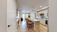 Located at 601 Belpree Dr in Plano, Texas, this thoughtfully designed 2-bedroom, 3-bathroom residence offers a cohesive open-concept floor plan with modern finishes and a bright, airy ambiance throughout. Light wood-style flooring flows seamlessly from the kitchen through the dining area and into the living room, creating a unified and welcoming feel.

The kitchen is a standout feature, showcasing light wood cabinetry, a subway tile backsplash, stainless steel appliances including a French door refrigerator, range, and over-the-range microwave, all anchored by a white quartz waterfall island with bar seating and stylish pendant lighting. A built-in desk area adjacent to the kitchen provides a convenient workspace.

The living room is bathed in natural light from large windows with floor-to-ceiling drapes, creating a warm and inviting retreat. The spacious primary bedroom features plush carpet, a ceiling fan, ample natural light, and direct access to a well-appointed en suite bathroom complete with a dual-sink vanity, marble-style tile walk-in shower with black hardware, and a dedicated walk-in closet with double hanging rods. A second full bathroom features a soaking tub surrounded by elegant marble-look tile. Each space reflects careful attention to detail, balancing comfort with contemporary design.