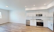 Located at 18355 SW 110th Ave in Miami, FL, this well-appointed 2-bedroom, 2-bathroom residence offers a thoughtfully designed single-floor layout with modern finishes throughout. The open-concept living and kitchen area serves as the heart of the home, featuring warm light wood flooring, recessed lighting, and a clean, airy aesthetic defined by crisp white walls. The kitchen is outfitted with sleek white cabinetry extending to the ceiling, light countertops, and a full suite of stainless steel appliances including a gas range, built-in microwave, dishwasher, and a large French door refrigerator. Both bedrooms are finished with the same warm wood flooring, ceiling fans, and natural light from windows with blinds. Each bedroom includes dedicated closet space with built-in shelving. The primary bedroom is generously sized and connects to a well-appointed en-suite bathroom featuring a dual-sink vanity with quartz countertops, a full-width mirror, and a glass-enclosed shower with tile surround. The second bathroom offers a single-sink vanity and a tiled shower-tub combination. Additional conveniences include a dedicated laundry area, utility room, and a central hallway connecting all spaces seamlessly.