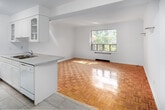 Located at 877 Avenue Rd in the desirable midtown Toronto neighbourhood of Forest Hill, this one-bedroom, one-bathroom suite offers a compact and efficiently laid-out single-floor residence. The living room is a bright, welcoming space featuring warm parquet hardwood flooring and a large window that frames lush greenery, allowing generous natural light to fill the room. The same classic parquet flooring continues throughout the living areas and into the bedroom, lending a sense of continuity and warmth across the suite. The kitchen is well-appointed with white cabinetry, tile flooring, a full suite of white appliances including a refrigerator and electric range, and a window overlooking the exterior — making it a functional and pleasant space for everyday cooking. The bedroom is a comfortable, well-proportioned room with its own window providing natural light and neighbourhood views, along with the same attractive hardwood underfoot. The bathroom features a full soaker tub with overhead shower, a pedestal sink, and light tile flooring, maintaining the suite's clean, bright aesthetic throughout. Crisp white walls and flush-mount lighting contribute to the overall airy, neutral ambiance of this well-located Toronto suite.